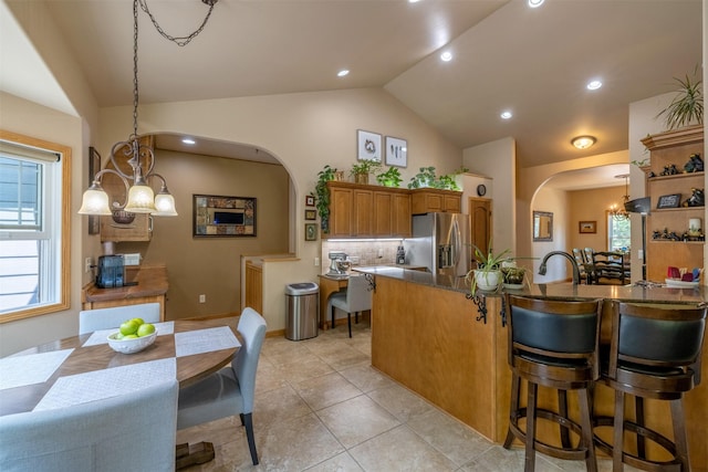 13 Crossfire Dr, Clancy, MT 59634 - kitchen with stainless steel refrigerator with ice dispenser, arched walkways, brown cabinets, lofted ceiling, and decorative backsplash