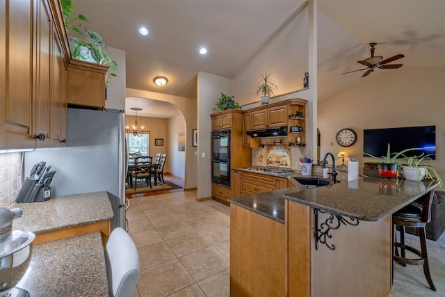 13 Crossfire Dr, Clancy, MT 59634 - kitchen featuring arched walkways, under cabinet range hood, a peninsula, backsplash, and brown cabinets