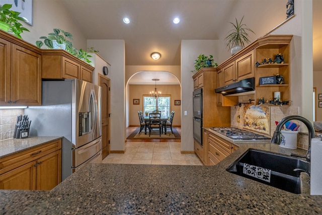 13 Crossfire Dr, Clancy, MT 59634 - kitchen featuring appliances with stainless steel finishes, under cabinet range hood, arched walkways, light tile patterned flooring, and dark stone counters