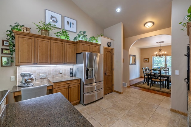 13 Crossfire Dr, Clancy, MT 59634 - kitchen with stainless steel fridge, a chandelier, arched walkways, brown cabinets, and tasteful backsplash