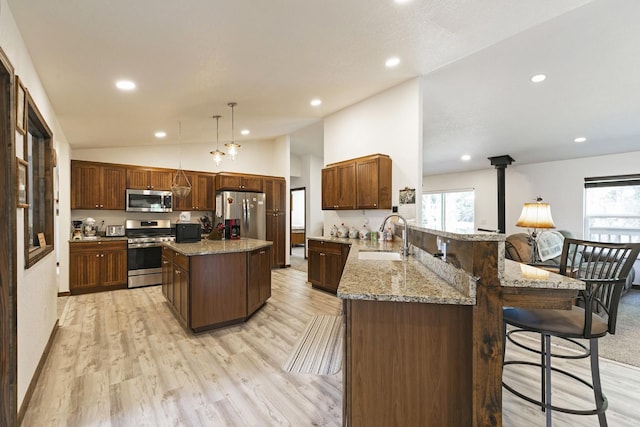 3979 Evenson Ln, Stevensville, MT 59870 - kitchen featuring appliances with stainless steel finishes, lofted ceiling, a peninsula, light wood finished floors, and light stone countertops