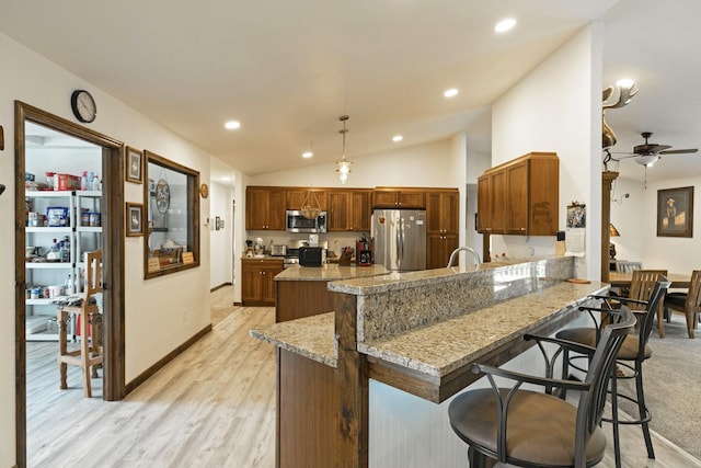 3979 Evenson Ln, Stevensville, MT 59870 - kitchen featuring appliances with stainless steel finishes, a peninsula, a kitchen bar, light wood-style flooring, and ceiling fan