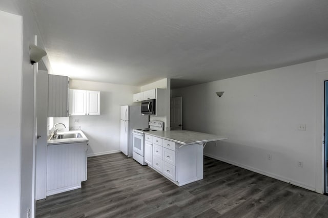 3979 Evenson Ln, Stevensville, MT 59870 - kitchen with white appliances, a peninsula, dark wood-type flooring, and white cabinetry