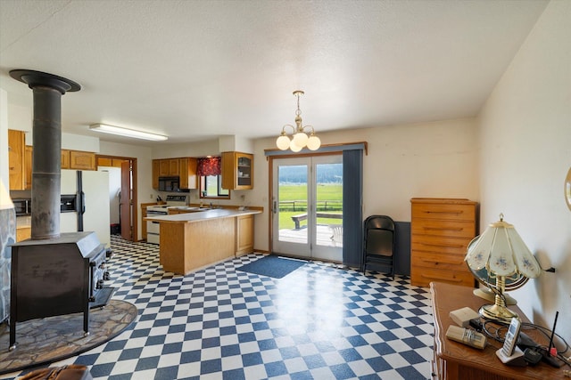 3250 US Highway 2 W, Kalispell, MT 59901 - kitchen featuring a wood stove, white appliances, a peninsula, tile patterned floors, and light countertops