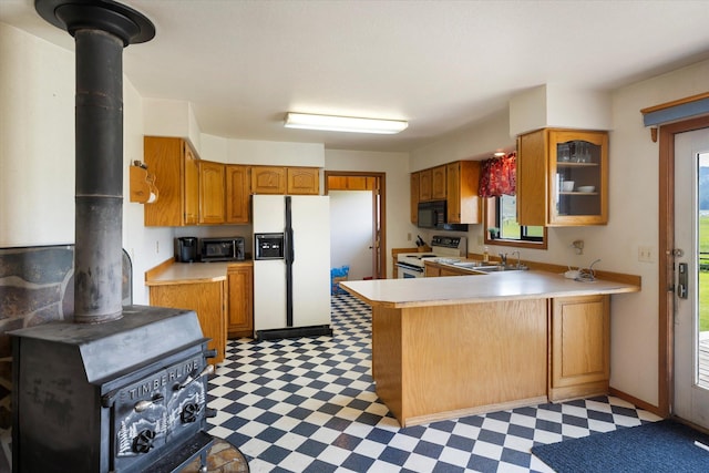 3250 US Highway 2 W, Kalispell, MT 59901 - kitchen featuring white appliances, a wood stove, light flooring, a peninsula, and light countertops