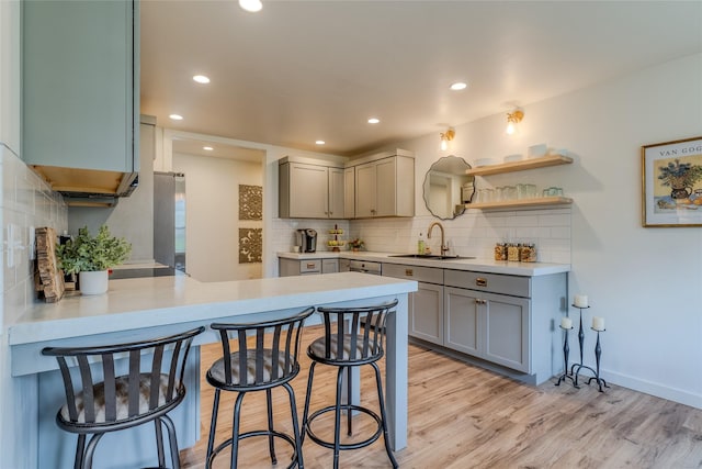 405 Kendal Loop, Kalispell, MT 59901 - kitchen with gray cabinets, backsplash, light wood finished floors, a kitchen bar, and light countertops