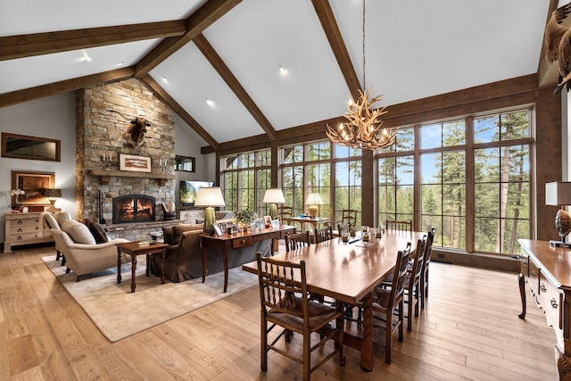 176 Whitefish Hills Loop, Whitefish, MT 59937 - dining space with high vaulted ceiling, a chandelier, a fireplace, beam ceiling, and light wood-type flooring