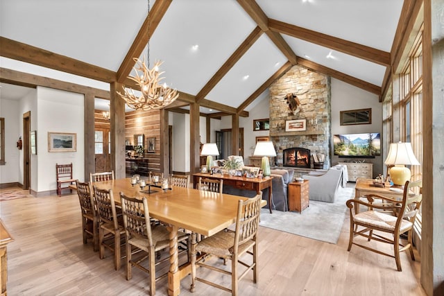 176 Whitefish Hills Loop, Whitefish, MT 59937 - dining space featuring a stone fireplace, light wood-style flooring, a chandelier, beamed ceiling, and high vaulted ceiling