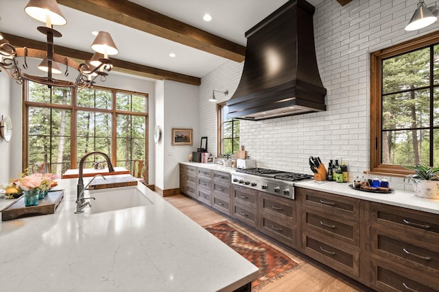 176 Whitefish Hills Loop, Whitefish, MT 59937 - kitchen featuring stainless steel gas stovetop, custom range hood, a chandelier, healthy amount of natural light, and beamed ceiling