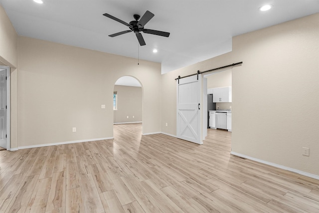 4012 Lancaster Rd, Missoula, MT 59808 - unfurnished living room with a barn door, a ceiling fan, light wood-style floors, arched walkways, and recessed lighting