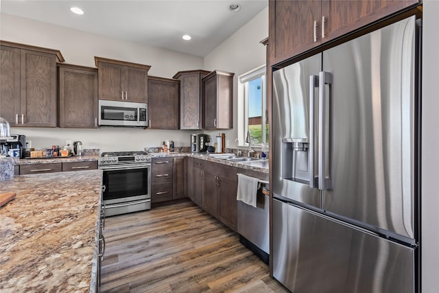 6910 Shaver Dr, Missoula, MT 59803 - kitchen featuring appliances with stainless steel finishes, dark brown cabinets, dark wood-type flooring, light stone counters, and recessed lighting