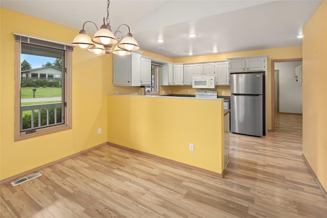 133 Trailridge Rd, Kalispell, MT 59901 - kitchen featuring freestanding refrigerator, white microwave, light wood finished floors, a peninsula, and a chandelier