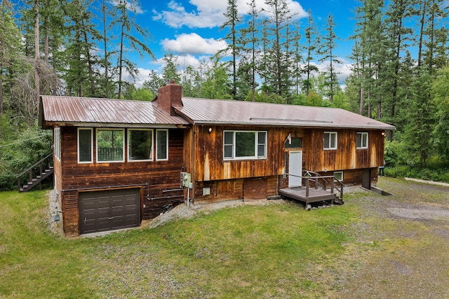1255 Tamarack Ln, Columbia Falls, MT 59912 - view of front facade featuring a garage, a metal roof, a front yard, a chimney, and driveway