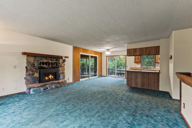 1255 Tamarack Ln, Columbia Falls, MT 59912 - unfurnished living room with dark colored carpet, a textured ceiling, a fireplace, and a ceiling fan