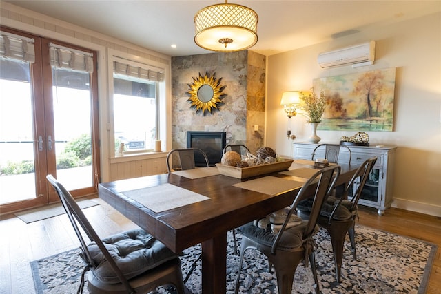 7175 US Highway 93 S, Lakeside, MT 59922 - dining space featuring a wall mounted AC, wood finished floors, a tiled fireplace, and french doors