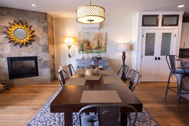 7175 US Highway 93 S, Lakeside, MT 59922 - dining area featuring wood finished floors, an AC wall unit, a fireplace, and recessed lighting