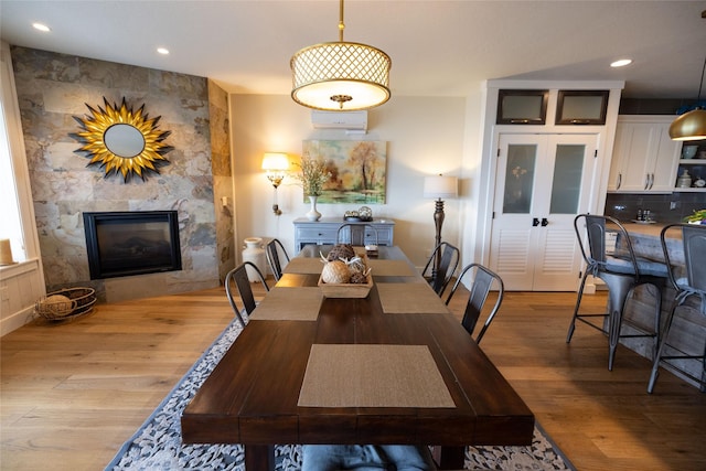 7175 US Highway 93 S, Lakeside, MT 59922 - dining room featuring wood finished floors, a large fireplace, recessed lighting, and a wall unit AC