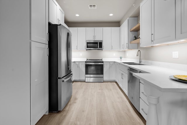 6201 Shiloh Ave Unit G, Whitefish, MT 59937 - kitchen with appliances with stainless steel finishes, light wood finished floors, light countertops, open shelves, and white cabinetry