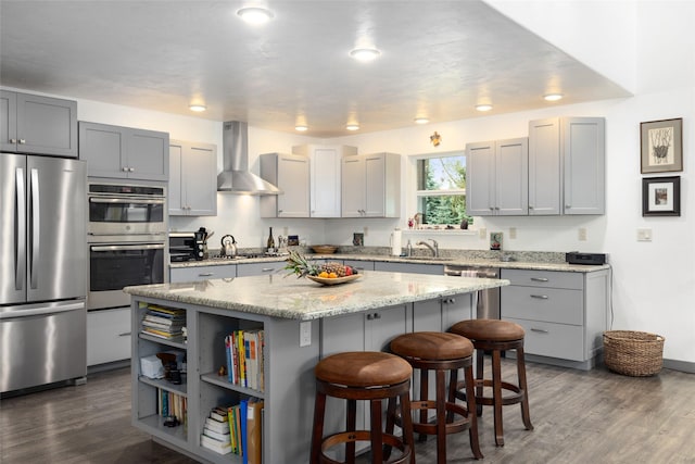 634 Country Way, Kalispell, MT 59901 - kitchen featuring stainless steel appliances, wall chimney exhaust hood, a center island, a kitchen bar, and dark wood-style floors
