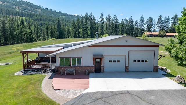 2206 US Highway 2 W, Kalispell, MT 59901 - view of front facade with a forest view, a front yard, brick siding, a wooden deck, and an attached garage