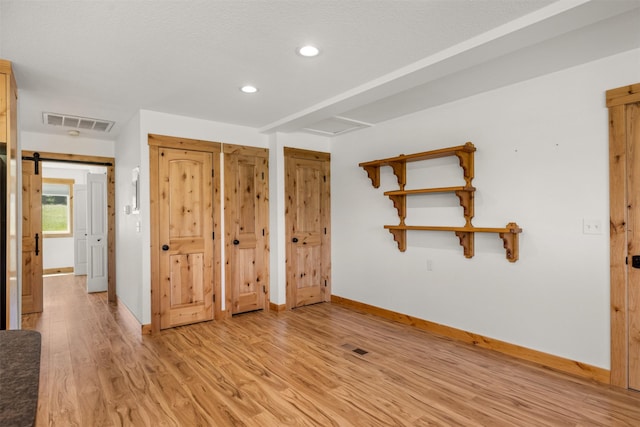 2206 US Highway 2 W, Kalispell, MT 59901 - unfurnished bedroom featuring light wood-style flooring, recessed lighting, and a barn door