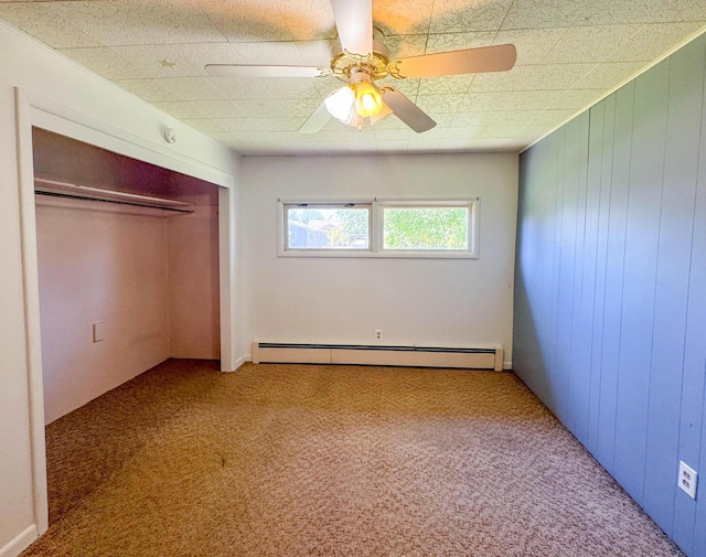1108 5th St E, Polson, MT 59860 - unfurnished bedroom featuring a baseboard heating unit, carpet, a closet, a ceiling fan, and wood walls