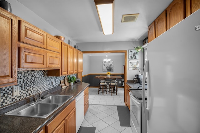 2321 8th Ave S, Great Falls, MT 59405 - kitchen featuring white appliances, light tile patterned floors, dark countertops, tasteful backsplash, and a chandelier