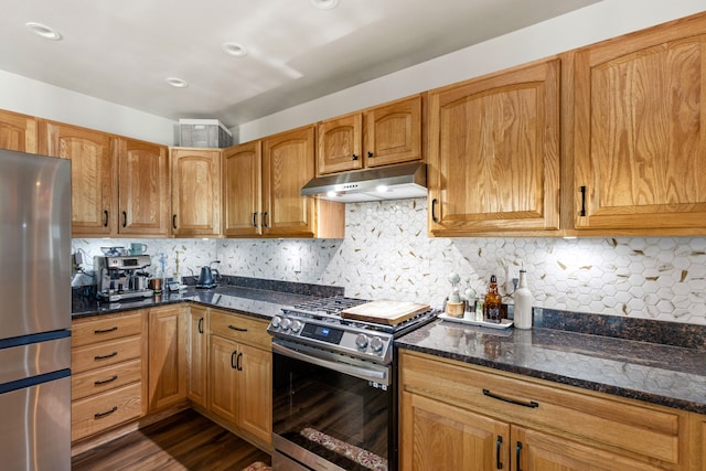 2604 5th Ave S, Great Falls, MT 59405 - kitchen with appliances with stainless steel finishes, under cabinet range hood, dark stone counters, dark wood finished floors, and backsplash