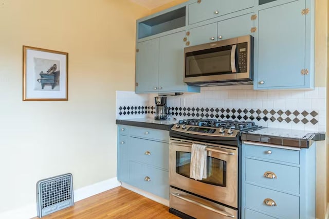 1046 3rd Ave E, Kalispell, MT 59901 - kitchen featuring appliances with stainless steel finishes, blue cabinets, tasteful backsplash, and light wood finished floors