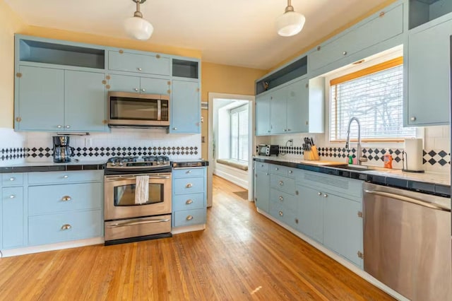 1046 3rd Ave E, Kalispell, MT 59901 - kitchen featuring stainless steel appliances, blue cabinetry, tasteful backsplash, tile counters, and light wood-style flooring