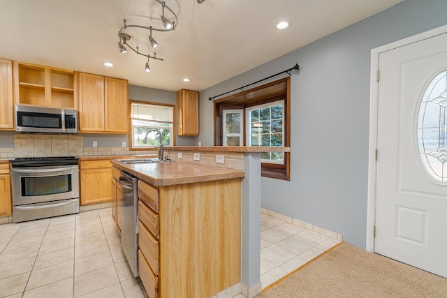 408 23rd Ave NE, Great Falls, MT 59404 - kitchen with stainless steel appliances, light tile patterned floors, decorative backsplash, an island with sink, and light brown cabinets
