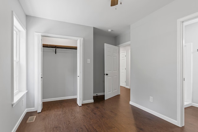 unfurnished bedroom featuring ceiling fan, a closet, and dark wood-type flooring