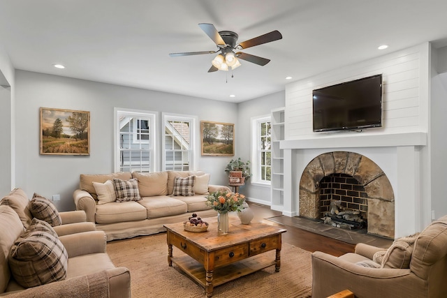 living room with a fireplace, wood-type flooring, and ceiling fan