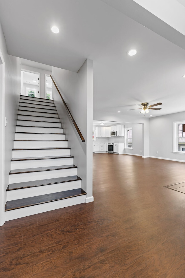 staircase featuring wood-type flooring and ceiling fan