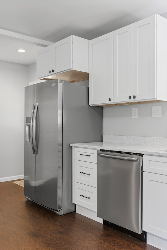 kitchen with dark hardwood / wood-style floors, light stone countertops, white cabinetry, and appliances with stainless steel finishes