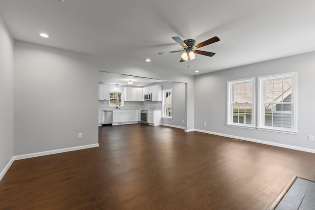 unfurnished living room with ceiling fan, dark hardwood / wood-style flooring, and sink