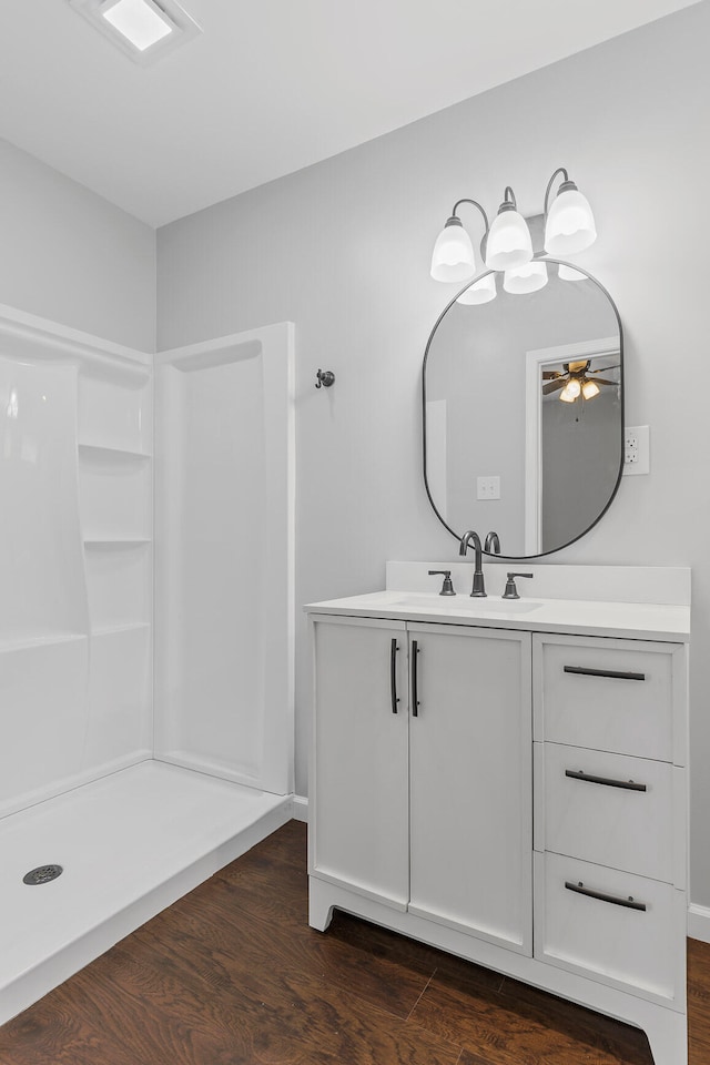 bathroom with hardwood / wood-style floors, ceiling fan, walk in shower, and vanity