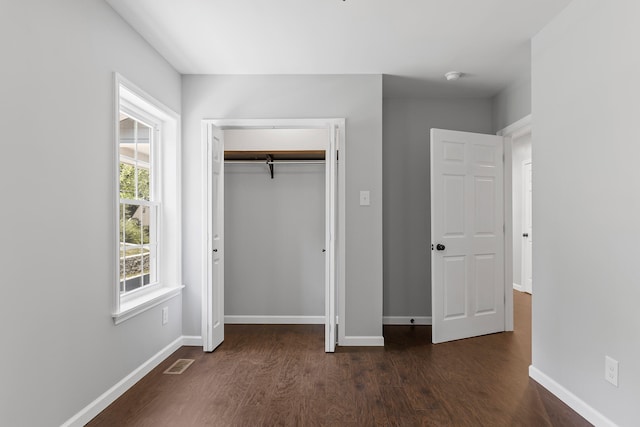 unfurnished bedroom featuring dark hardwood / wood-style flooring and a closet