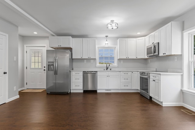 kitchen with pendant lighting, sink, dark hardwood / wood-style floors, appliances with stainless steel finishes, and white cabinetry