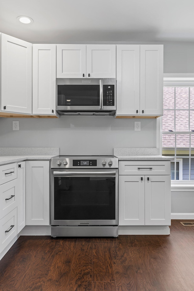 kitchen featuring white cabinets, dark wood-type flooring, and appliances with stainless steel finishes