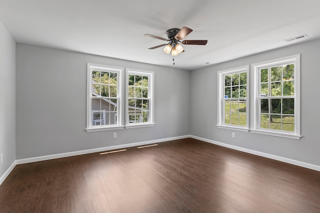 unfurnished room with ceiling fan, dark wood-type flooring, and a healthy amount of sunlight