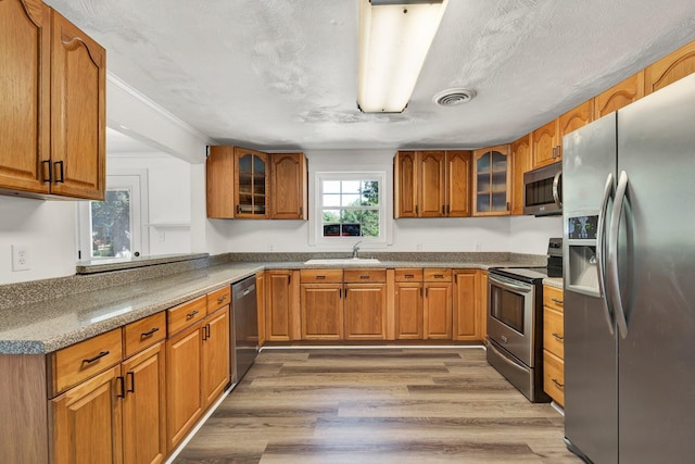 kitchen with appliances with stainless steel finishes, sink, a textured ceiling, and hardwood / wood-style floors