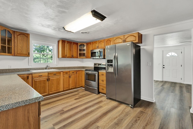 kitchen featuring a textured ceiling, sink, appliances with stainless steel finishes, and light hardwood / wood-style flooring