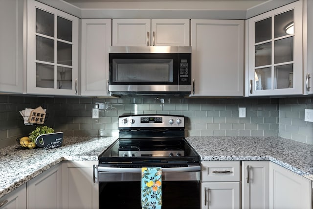 kitchen featuring backsplash, stainless steel appliances, white cabinets, and light stone countertops