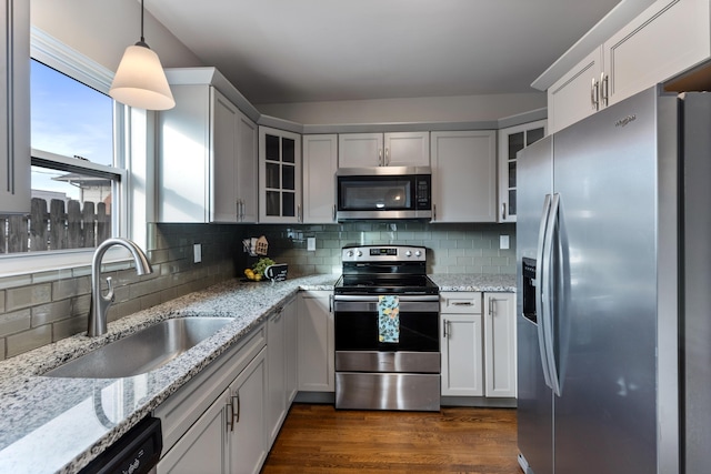 kitchen with sink, dark hardwood / wood-style floors, pendant lighting, stainless steel appliances, and light stone countertops