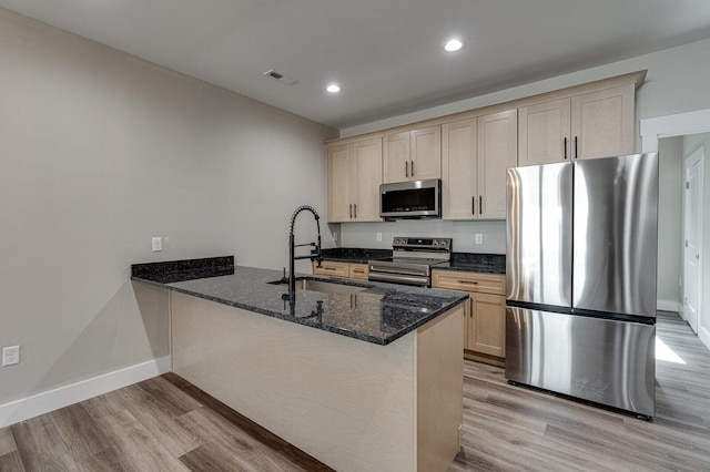 kitchen featuring dark stone countertops, sink, kitchen peninsula, and appliances with stainless steel finishes