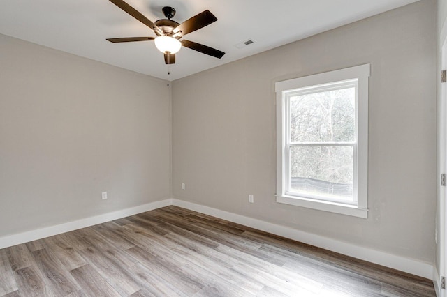 spare room featuring a wealth of natural light, light hardwood / wood-style floors, and ceiling fan