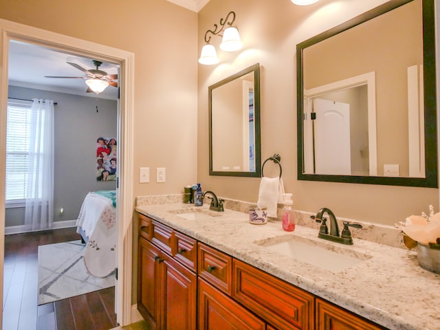 full bathroom with wood finished floors, a sink, baseboards, and double vanity