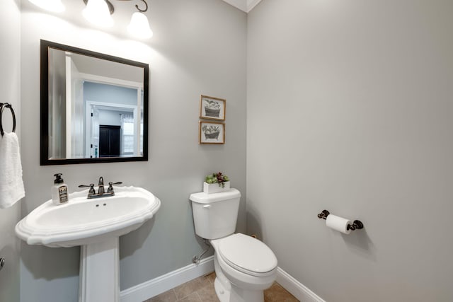 half bathroom with tile patterned floors, toilet, and baseboards