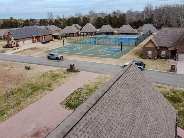 view of basketball court featuring a tennis court, a residential view, and fence